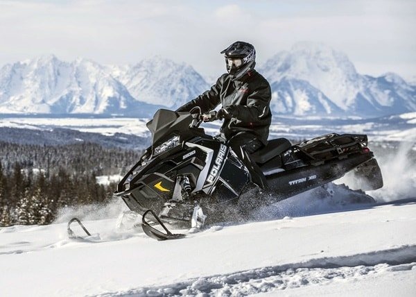 image d'un homme en habis sportif sur sa motoneige polaris noire