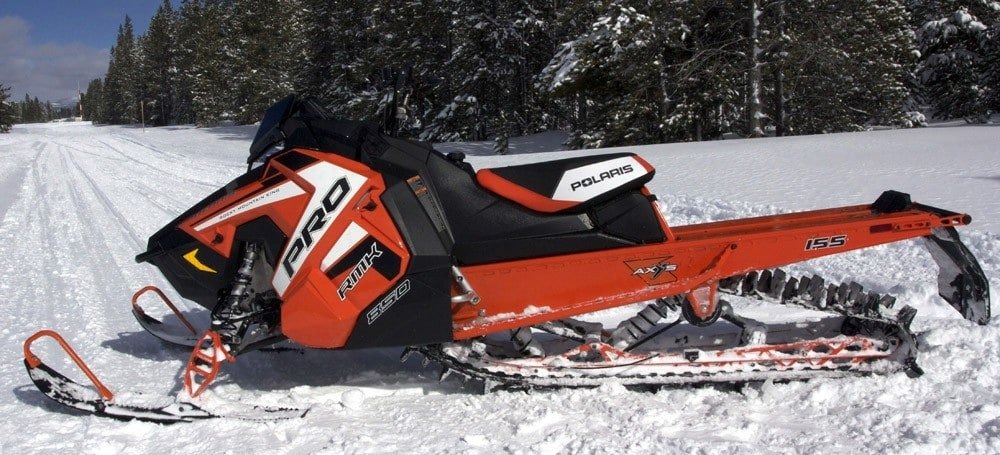 image of a man driving his red polaris snowmobile