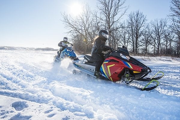 Image of two persons driving their polaris indy EVO outside in the snow 